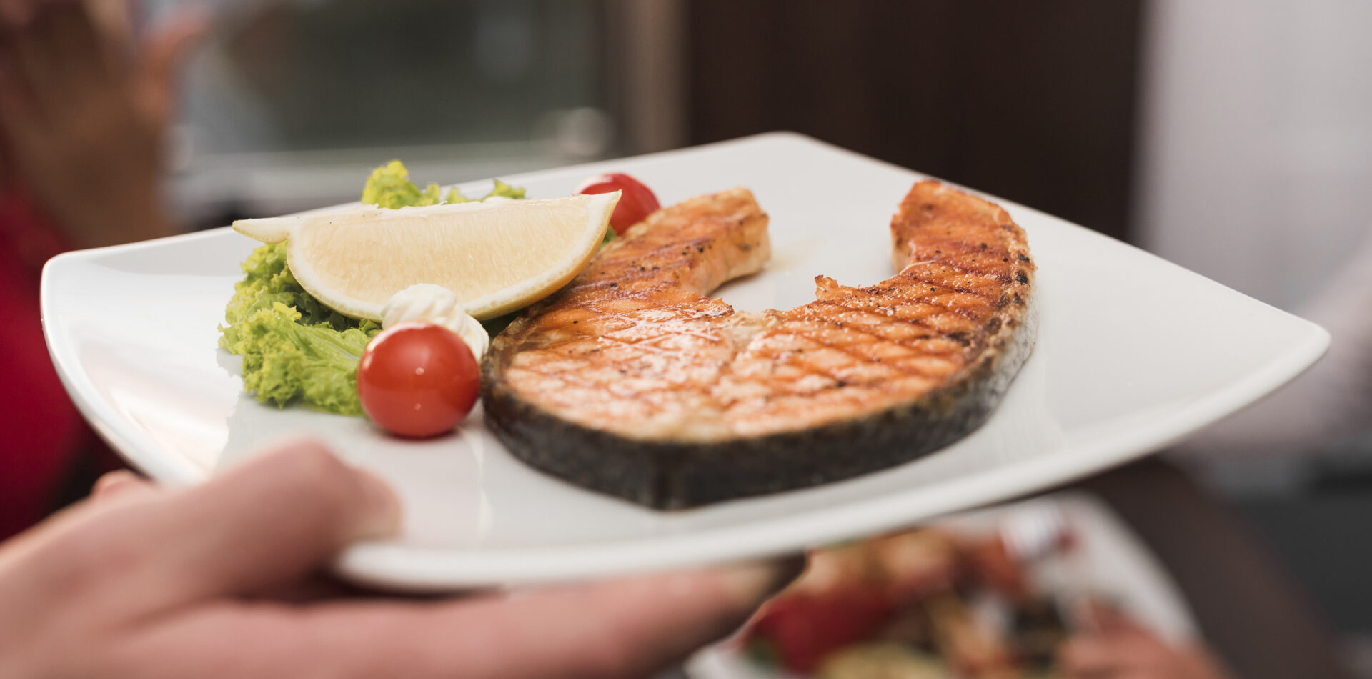 Beyaz bir tabakta, taze ve lezzetli görünen ızgara somon balığı servise hazır şekilde sunulmuş.