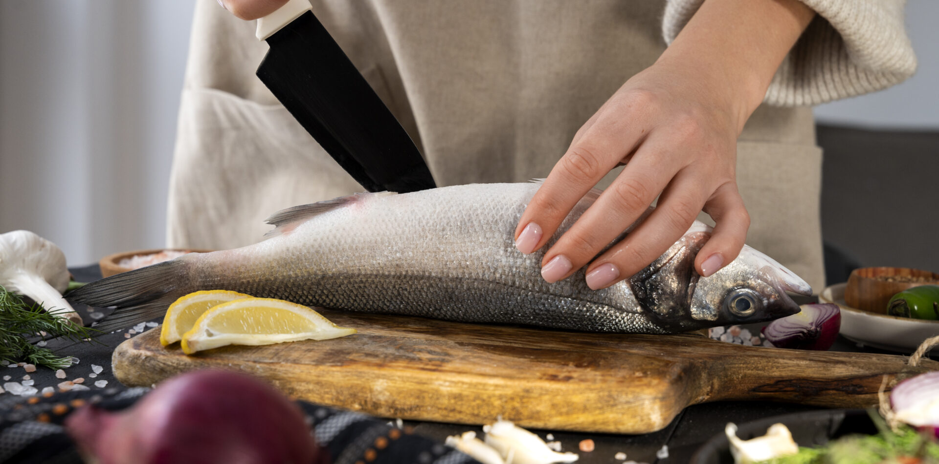 Aşçı, mutfak tezgahında balık temizliyor.