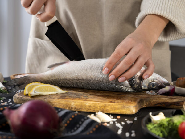 Aşçı, mutfak tezgahında balık temizliyor.