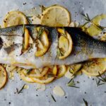 Limonun deniz levreği altında güzel bir sunum ve yeşilliklerle pişmeye hazır.