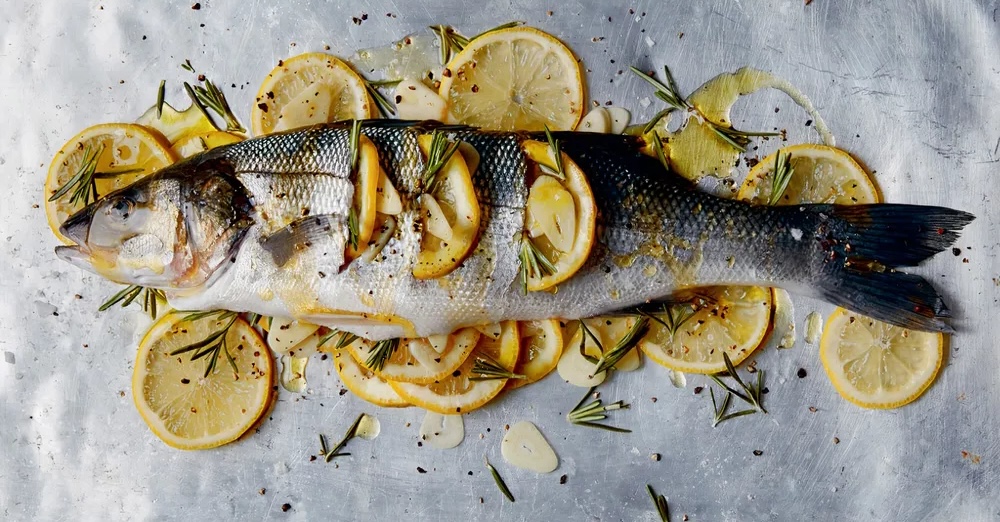 Limonun deniz levreği altında güzel bir sunum ve yeşilliklerle pişmeye hazır.