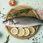 Somon balığın üzerinde otlar ve limon dilimleri bulunan bir tabak (kuşbakışı görünüm)