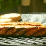 Somon balığı ızgarada pişirilmiş ve doğrudan ızgara üzerinde sunulmuş olarak görünüyor.