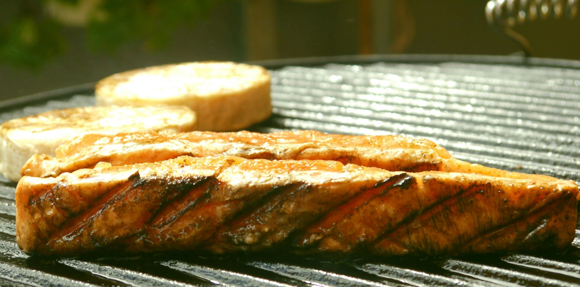 Somon balığı ızgarada pişirilmiş ve doğrudan ızgara üzerinde sunulmuş olarak görünüyor.